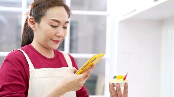 4K亚洲女人用智能手机拍摄面包店在厨房的社交媒体上做广告