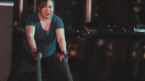 慢动作身体积极亚洲华人中成年妇女在健身房练习战斗绳在晚上