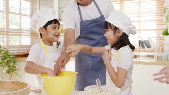快乐微笑的年轻亚洲日本家庭与学龄前的孩子在现代厨房家庭的早餐做蛋糕的乐趣和欢笑