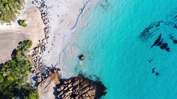 上面温和的海浪拍打着原始清澈的海湾有白色的沙子和岩石