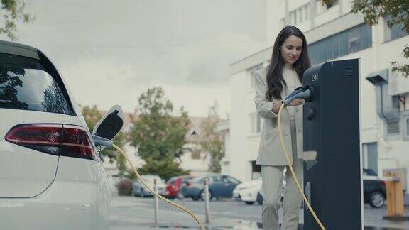 一名女子在为她的电动汽车充电时进行移动支付