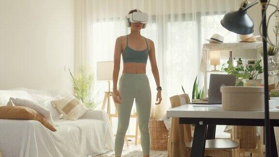 年轻的亚洲女运动员戴着虚拟现实耳机在家里的客厅锻炼饮食和健康减肥
