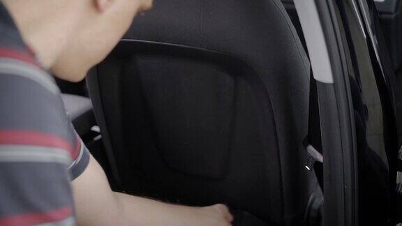 一个男人用海绵清洁和擦拭汽车座椅的背面的特写镜头