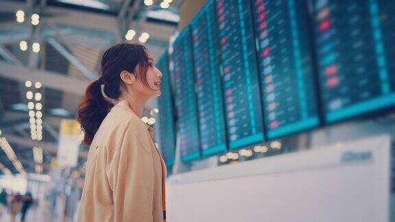 亚洲女性旅客在机场候机楼查看航班时刻表旅游旅行概念