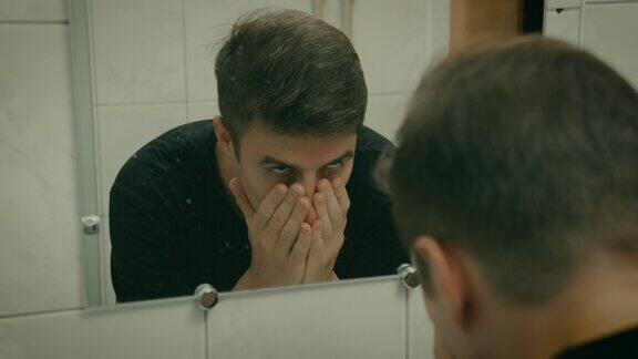 一个男人在浴室洗脸时镜子里的影像慢动作