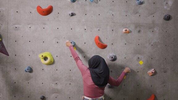 女性穆斯林攀岩者攀岩墙与安全安全带室内健身房