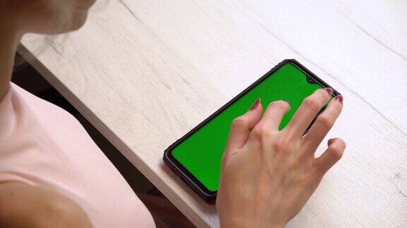 一个女孩在修指甲时使用了绿色屏幕的智能手机独有的美甲服务美甲师用粉红色的凝胶指甲油涂指甲指甲修剪整齐的红色指甲油的应用程序
