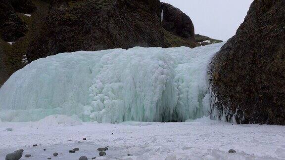 冰岛冰冻瀑布的特写与冰冷的岩石和流动的水冰冻的冬季景观与冰雪神奇的大自然冬天纯净的冰川水著名的旅游景点