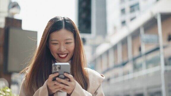 亚洲女人走路和使用智能手机