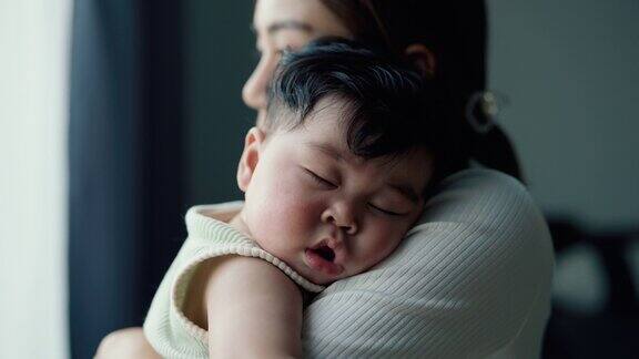 美丽的母亲抱着可爱的婴儿在家里睡觉