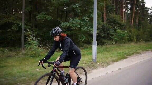 职业女子自行车手森林训练骑自行车上坡准备比赛跟踪射击