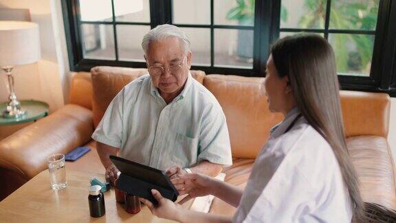 家访期间健康访视员用平板电脑向一位老人询问