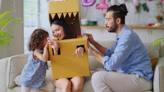 幸福的一家人父母和女儿孩子女孩在家里玩恐龙狩猎爸爸穿着手工制作的服装纸板怪物追逐妈妈和女儿与乐趣和快乐的退出客厅