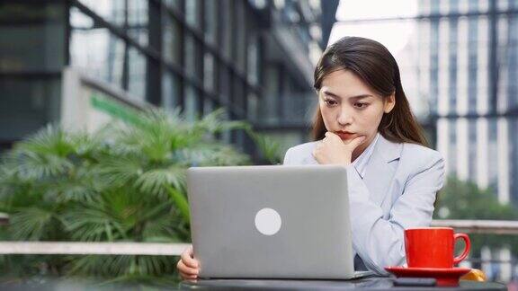年轻的亚洲女性工作在路边咖啡馆使用笔记本电脑