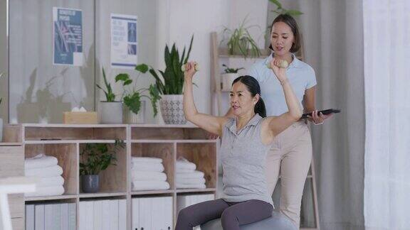 治疗康复或药片和一位亚洲女性物理治疗师与一位老年患者一起工作保健健身或恢复和女性举哑铃在物理治疗锻炼
