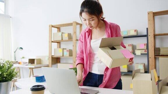 年轻的亚洲企业家女商人检查产品采购订单上的库存并保存到电脑笔记本电脑工作在家里的办公室