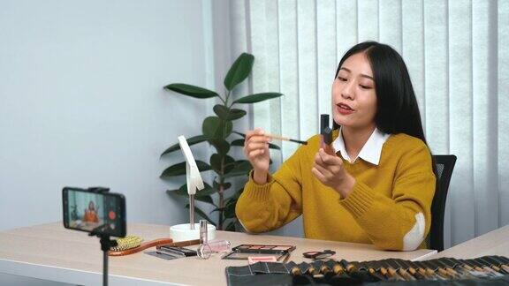 一位亚洲女性在博客上向她的朋友展示她的化妆配件并解释如何使用