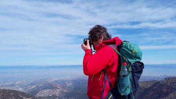 摄影师登山者正在山顶上用单反相机拍摄风景