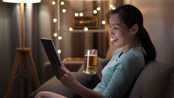 亚洲女人在视频电话会议与朋友做快乐的时间在她的手啤酒