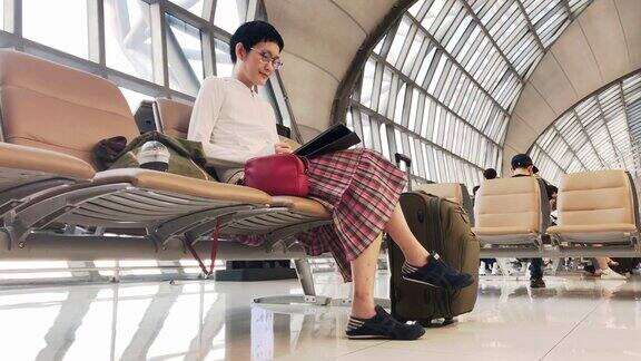 亚洲妇女在机场航站楼使用平板电脑