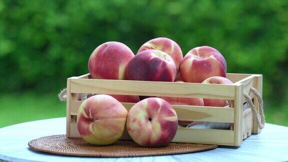 在模糊的绿色背景上的新鲜桃子切片桃果在木篮子在花园木桌上