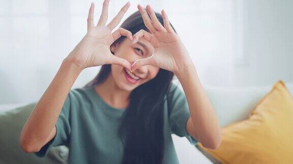 特写快乐的年轻亚洲妇女微笑和显示手标志心形看着相机健康心脏健康人寿保险爱心慈善志愿社会工作