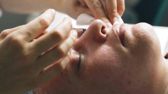 专业美容师用抗菌湿巾擦拭女性面部俯视图