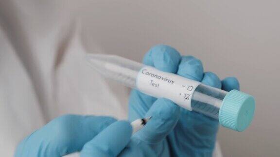 实验室工作人员戴着蓝色橡胶手套正在试管上填充阳性冠状病毒