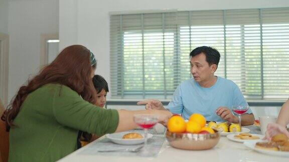 幸福的亚洲家庭在家里的餐桌上一起吃早餐