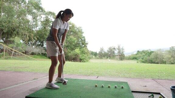 亚裔华裔女高尔夫球手在练习场练习挥杆