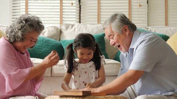 一对亚洲老夫妇在家里和一个小女孩一起玩高级生活方式家庭理念