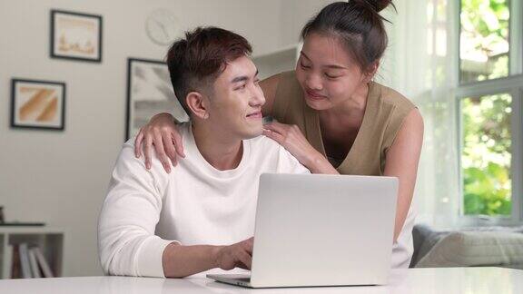 年轻的亚洲夫妇使用笔记本电脑年轻夫妇爱的时刻幸福观念