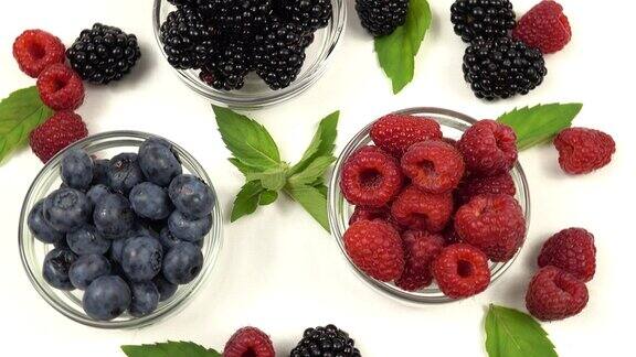 白色的桌子上放着小碗的覆盆子、黑莓和蓝莓