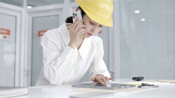 年轻漂亮的亚洲女工程师戴黄色头盔使用平板设计