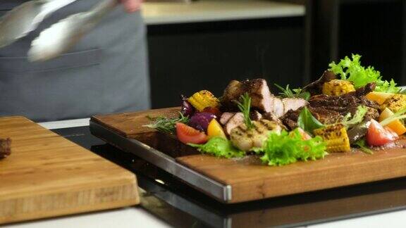 厨师用刀把炸好的肉片切好再配上烤好的蔬菜放在板上