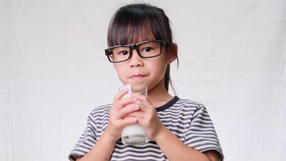 可爱的女生在上学前用杯子喝牛奶儿童健康营养回到学校概念