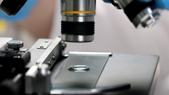 化学家科学家在显微镜下检查玻片上的液滴近距离4k电影慢动作
