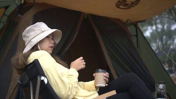 早上在帐篷前喝热咖啡的女人