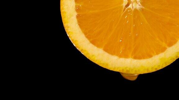 实时:水滴从橙色切片上落在黑色上