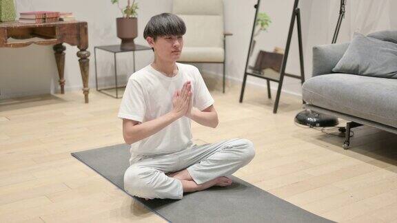 年轻的亚洲男子在家冥想瑜伽垫