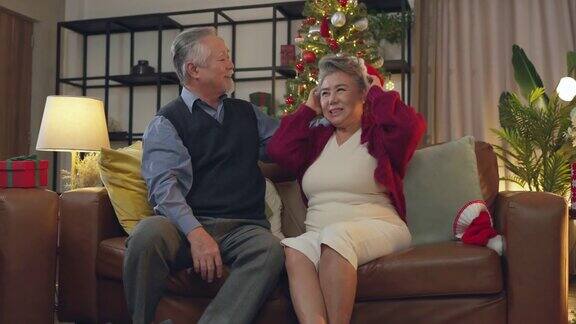 老长辈老长辈亚洲退休夫妇在沙发上一起享受着快乐的谈笑和快乐的在家亚洲老长辈成熟的成年人呆在家里隔离圣诞节日的背景