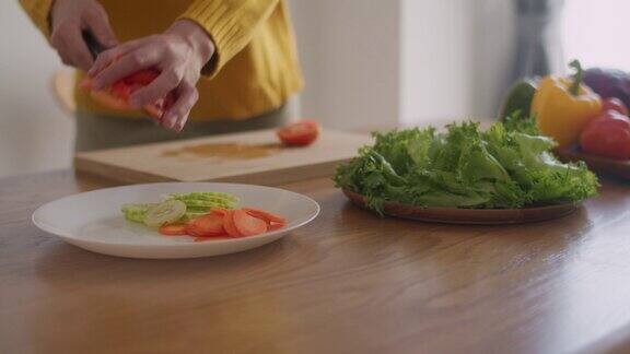 一名妇女在砧板上切西红柿的特写准备早上在家做沙拉的食物