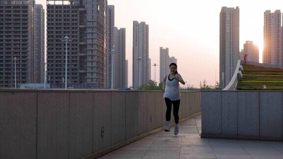 年轻的亚洲女性在城市的早晨在户外跑步
