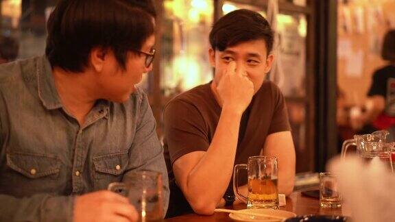 三杯两亚洲男人在居酒屋日本酒吧餐厅喝酒聊天
