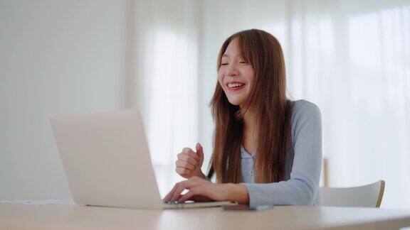年轻的亚洲妇女在家里用笔记本电脑工作在家办公视频会议视频通话学生在线学习课堂会议会议