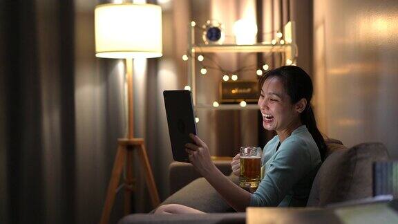 亚洲女人在视频电话会议与朋友做快乐的时间在她的手啤酒