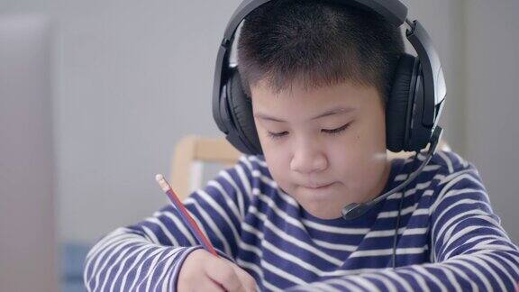 新常态亚洲男孩上网学习看着屏幕笔记本电脑开心地笑在家里开心地笑技术教育