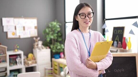 年轻的中国女幼儿园老师微笑着自信地拿着写字板