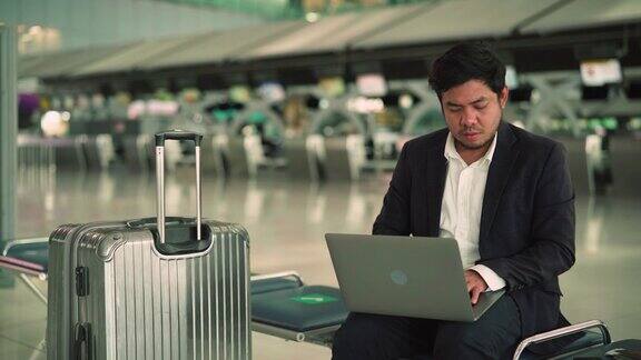 在机场等候时使用笔记本电脑的商人