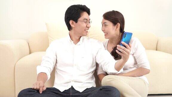 幸福的亚洲夫妇在家里客厅用智能手机与朋友和家人进行视频通话居家隔离保持社交距离扬已婚观念